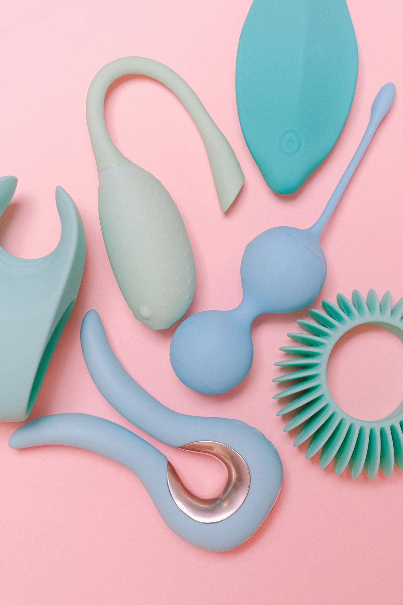 Pastel mint and blue vibrators and intimate accessories on a pink backdrop